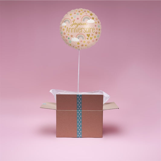 Ballon Arc-en-Ciel Joyeux Anniversaire en hélium flottant au-dessus d’une box cadeau rose Lune des Cœur.