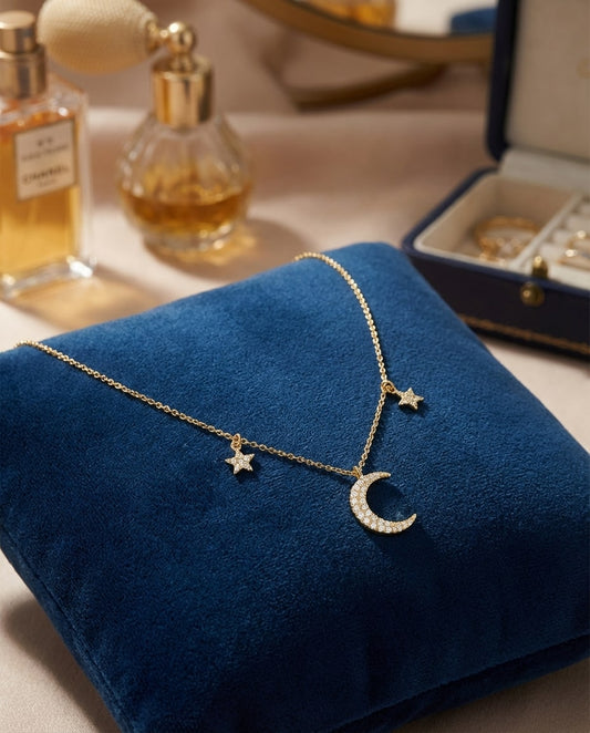 Collier lune et étoiles en or avec pendentif serti de pierres, présenté sur coussin en velours bleu dans un écrin élégant, bijou raffiné et féminin