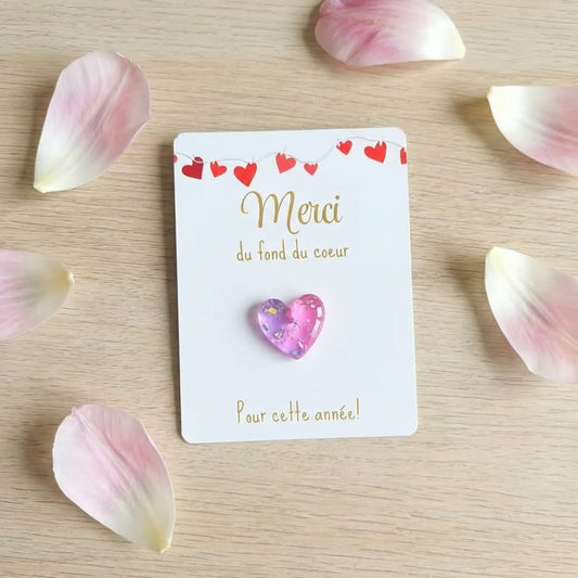 Carte Merci avec cœur en résine rose pailleté, décorée de lavande et d’un coffret cadeau sur une table en bois