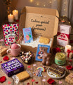 Box cadeau Lune de Cœur ouverte avec friandises, biscuits personnalisés, chocolat en forme de cœur, bonbons vegan et petits cadeaux originaux, présentée sur une table en bois avec fleurs et décoration. Coffret cadeau personnalisé prêt à offrir.