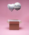 Ballons argent en forme de cœur et ballon rond Happy Birthday dans une box cadeau sur fond rose
