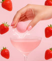 Bombe à cocktail fraises des bois tenue au-dessus d’un verre rose