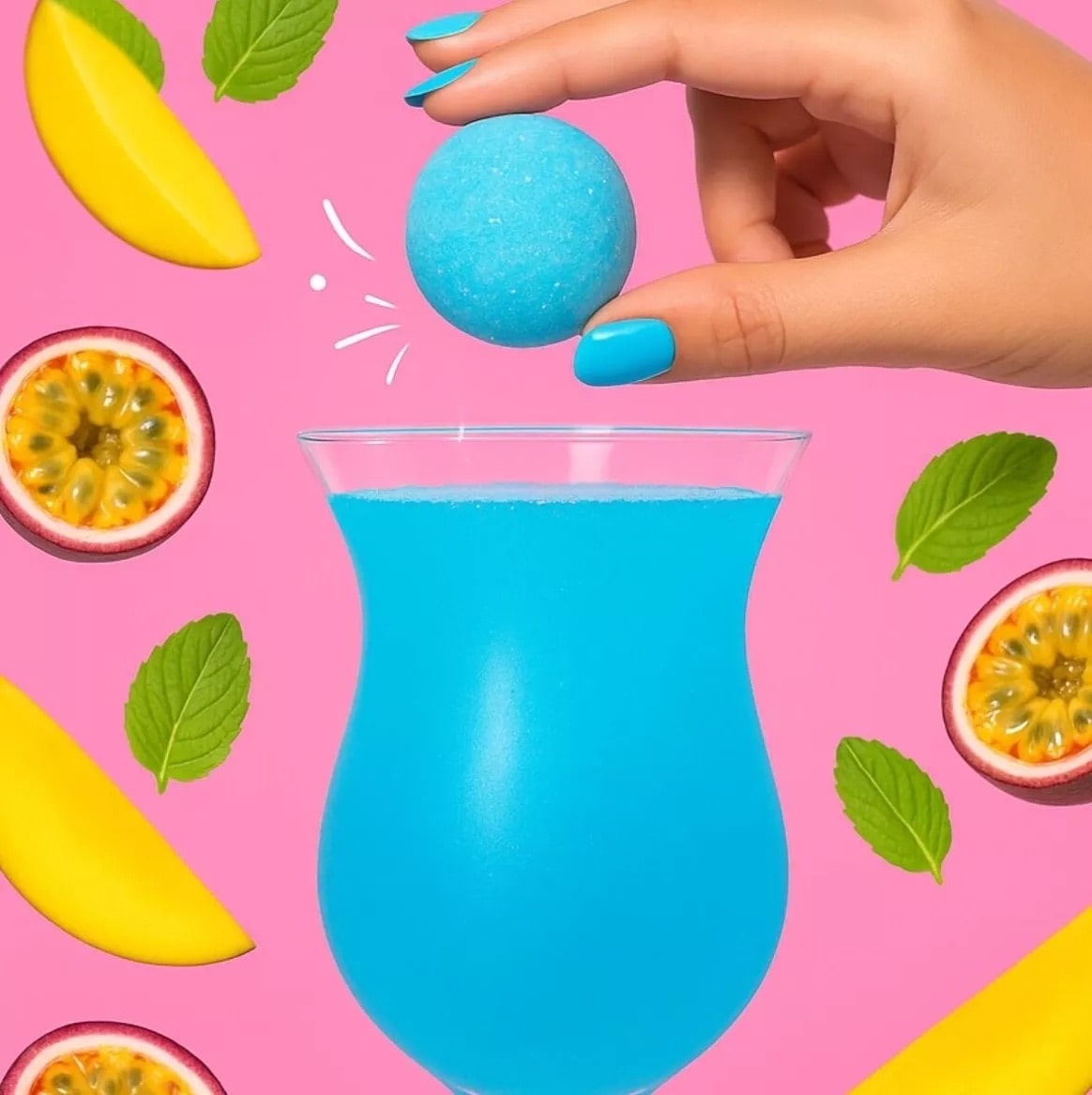 Bombe à cocktail tropicale bleue tenue au-dessus d’un verre, mangue et passion en décor