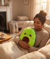 Femme utilisant une bouillotte peluche avocat sur un canapé dans une ambiance zen