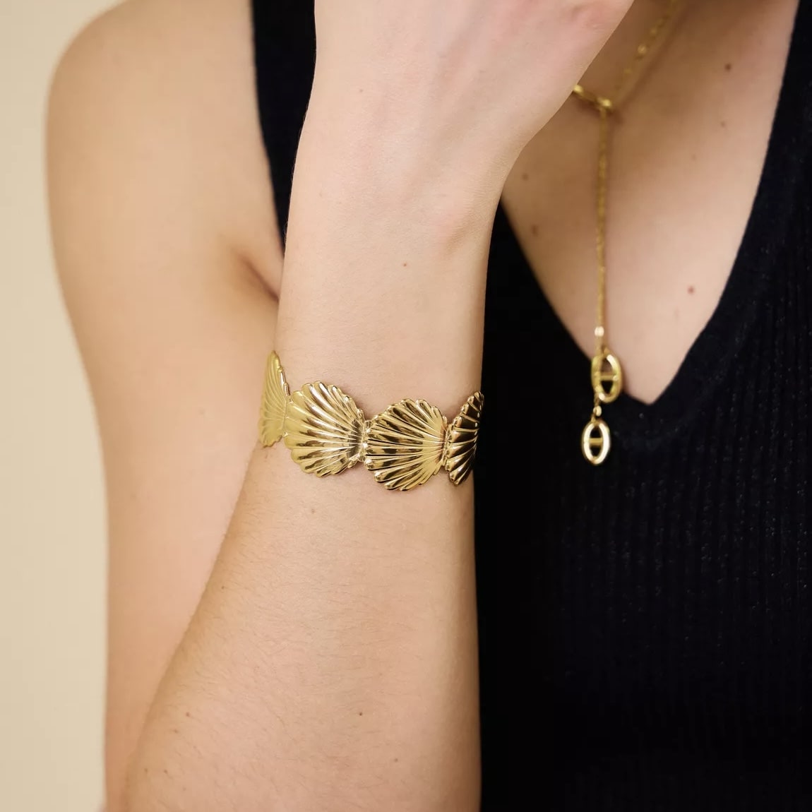 Bracelet coquillage porté au poignet féminin – bijou doré chic