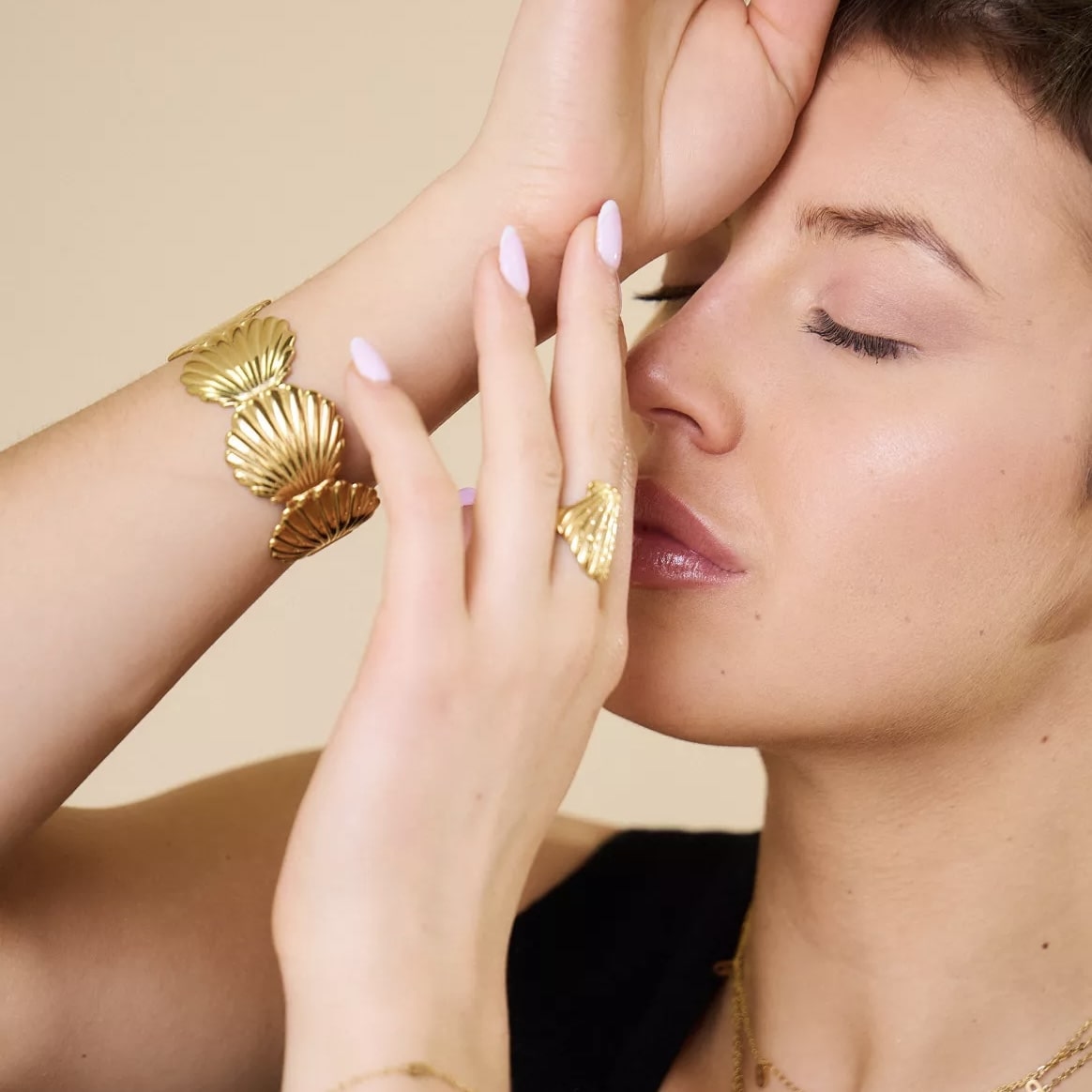 Bracelet coquillage porté au poignet féminin – bijou doré chic