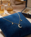 Collier lune et étoiles en or avec pendentif serti de pierres, présenté sur coussin en velours bleu dans un écrin élégant, bijou raffiné et féminin